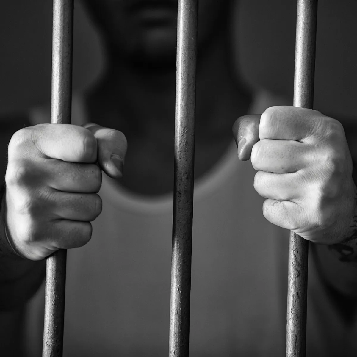 Hands grasping prison bars 