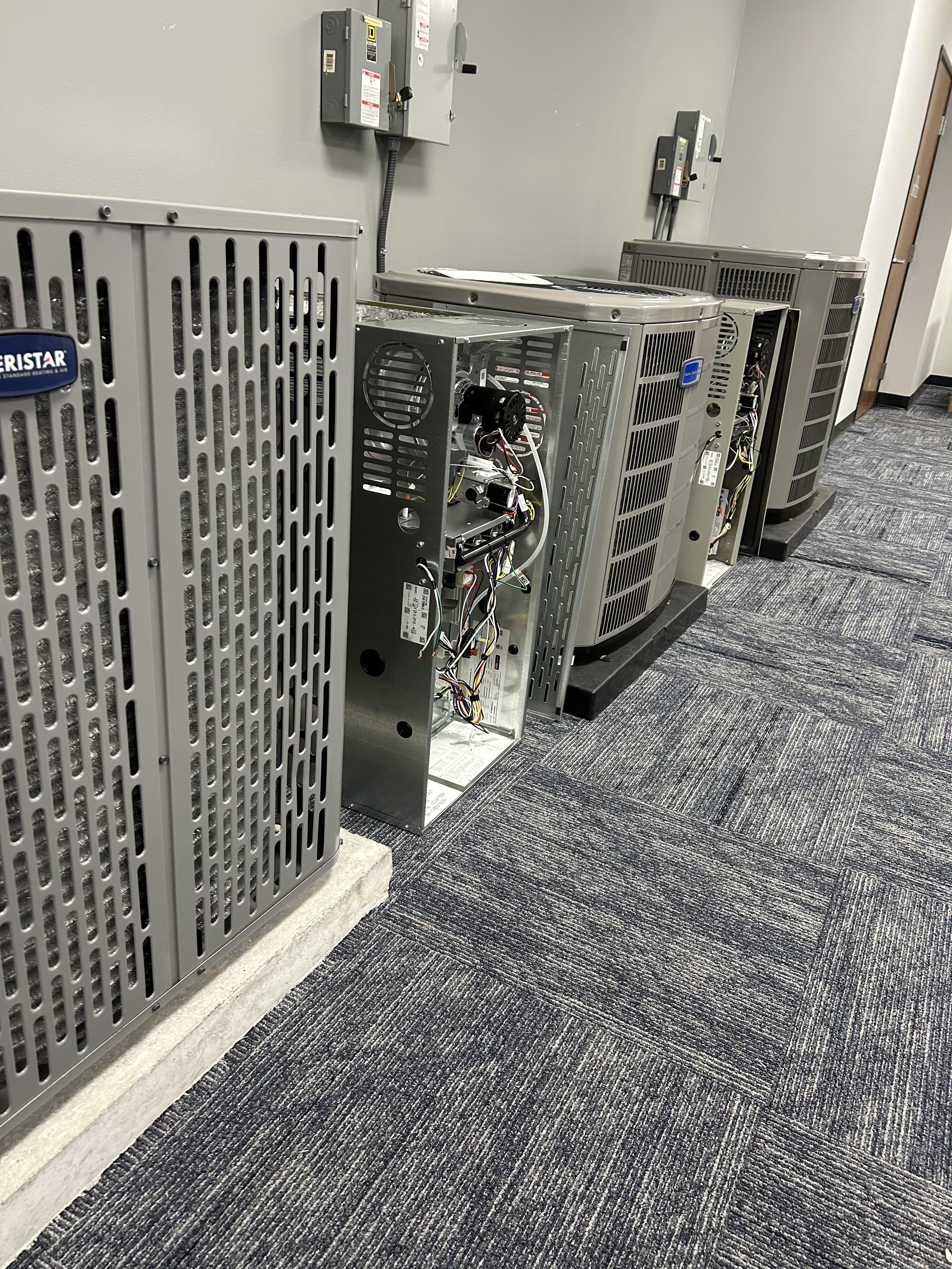 Air conditioning units lined up against a wall, showcasing energy-efficient HVAC systems ready for installation, emphasizing reliable cooling solutions for Oklahoma City homes.