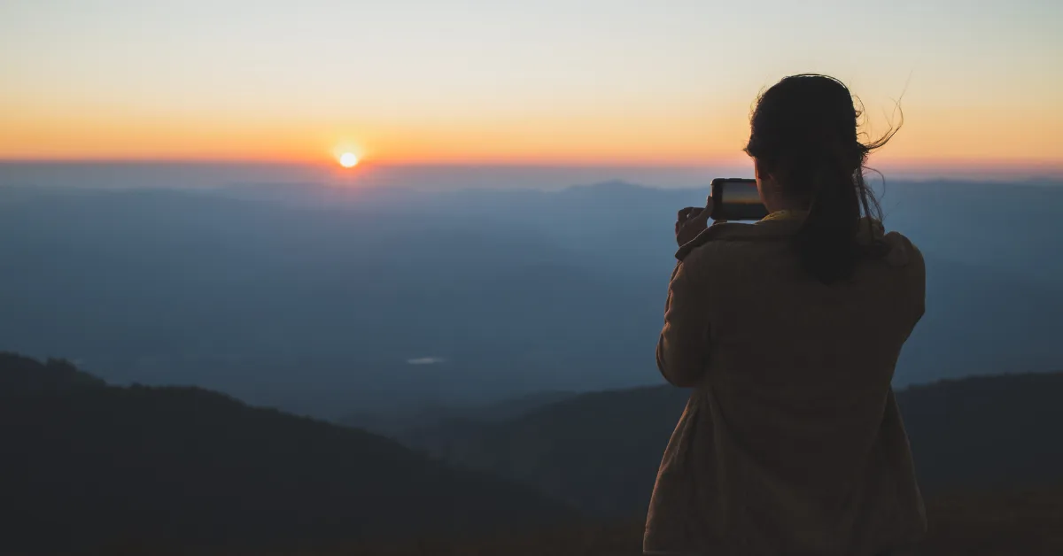 A Woman Taking a photo ofa sunset