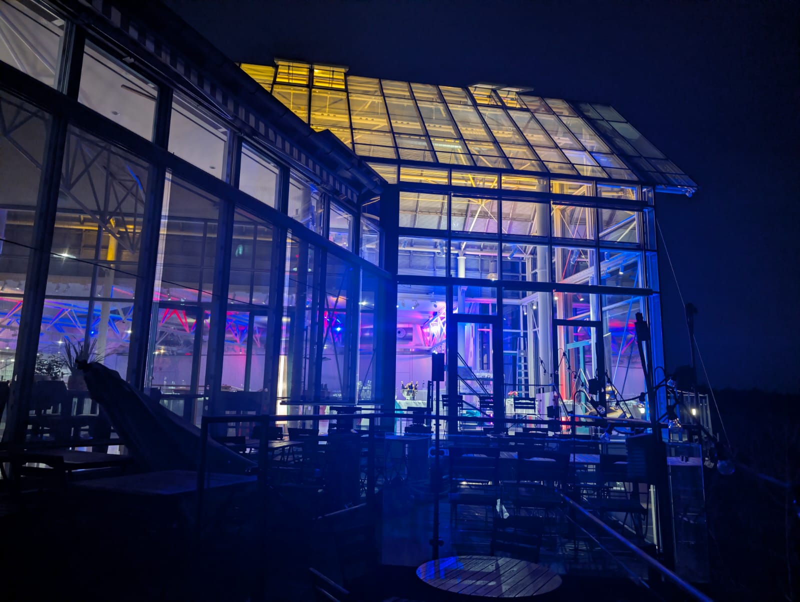 Night-time architectural glass building with colorful interior lights, representing Didis Kitchen bistro mood