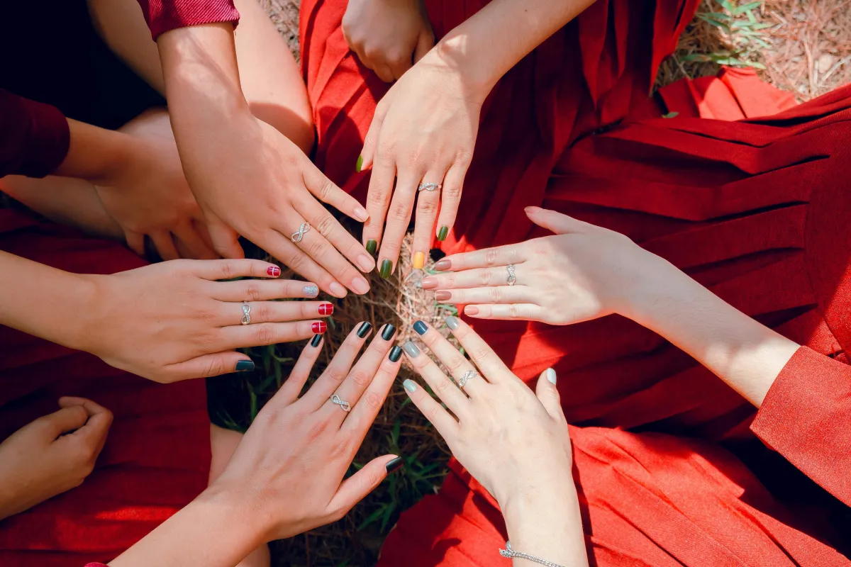 Women gathered in a healing circle, their hands joined at the center