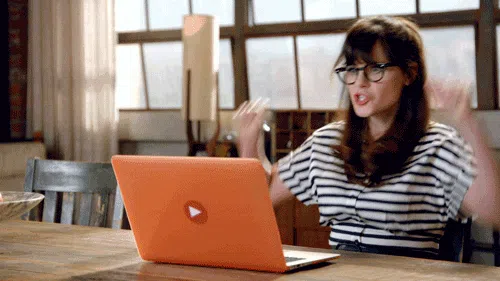 Animated gif of a woman in glasses cheering excitedly at her laptop, celebrating a win.