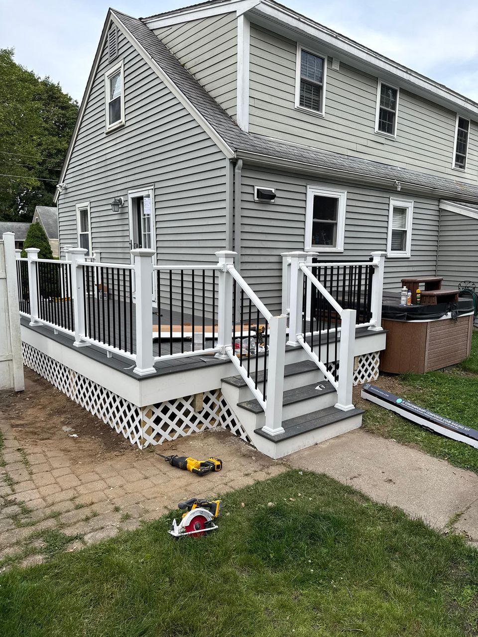 New composite deck and stairs with white railings and black balusters on a gray house