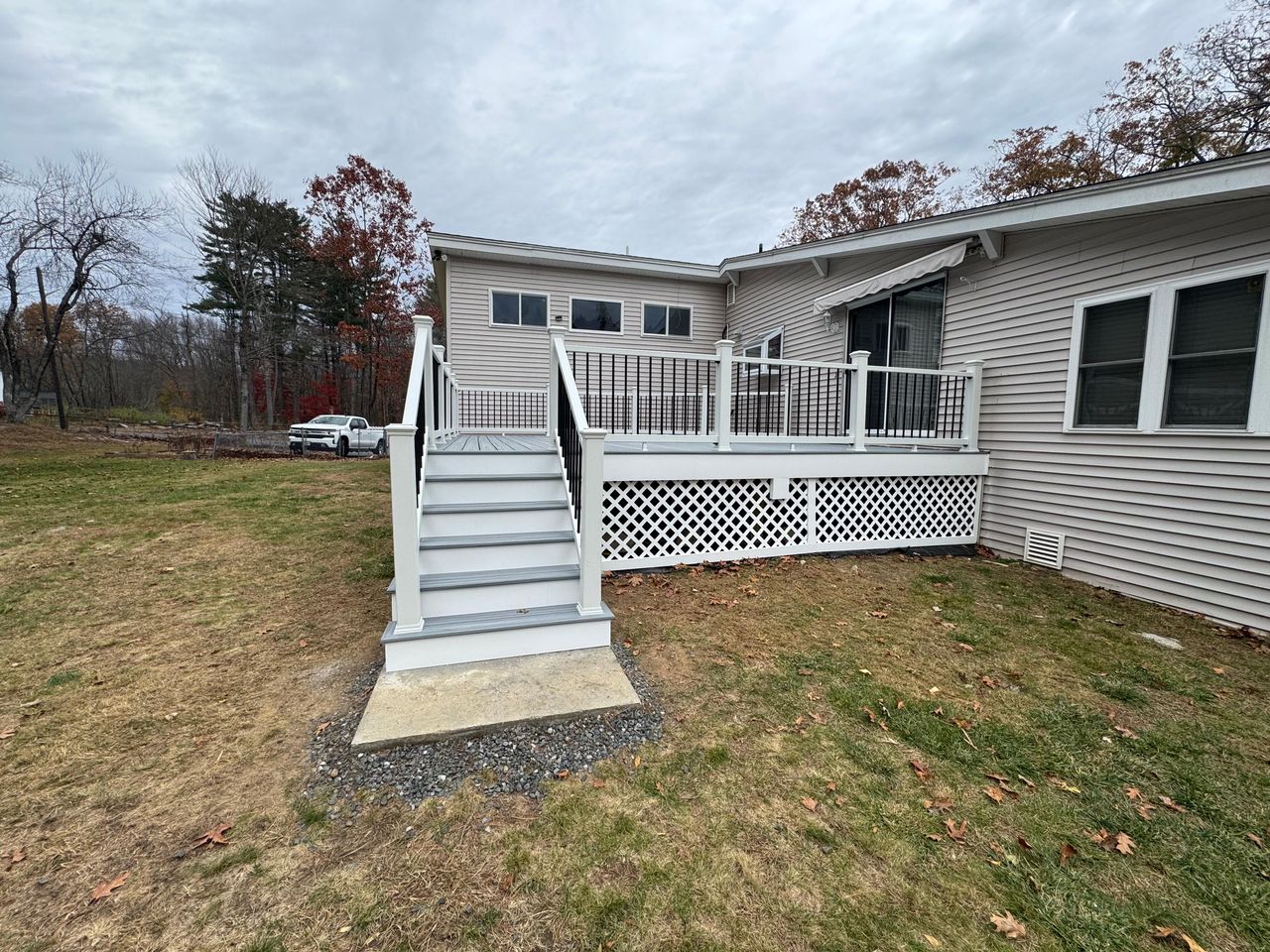 Composite deck with white railings, gray stair treads, and white lattice skirting