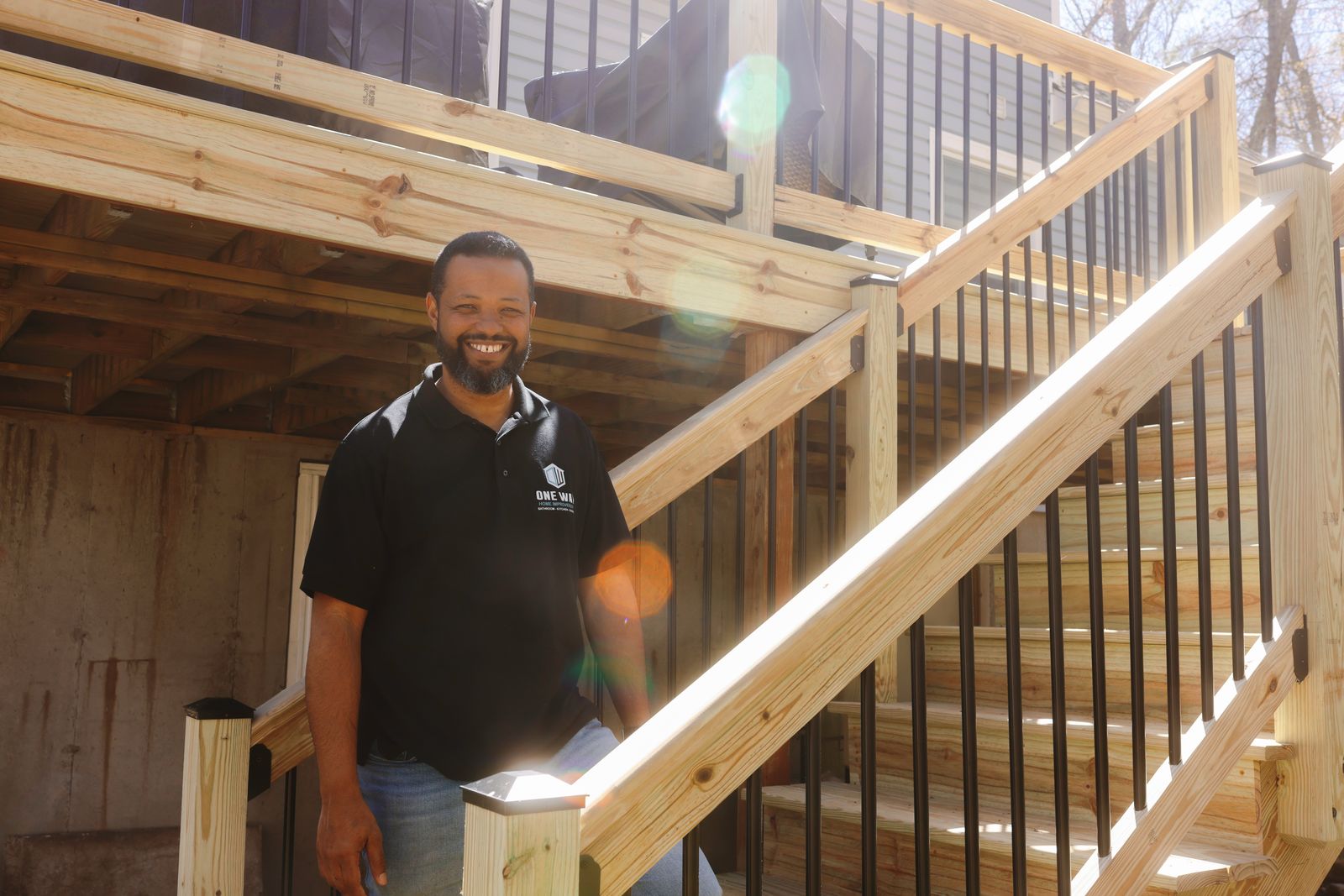 Smiling One Way team member on a newly built wooden deck staircase