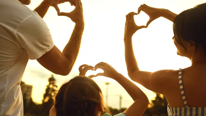 A family joyfully forming a heart shape with their hands, symbolizing love and togetherness.