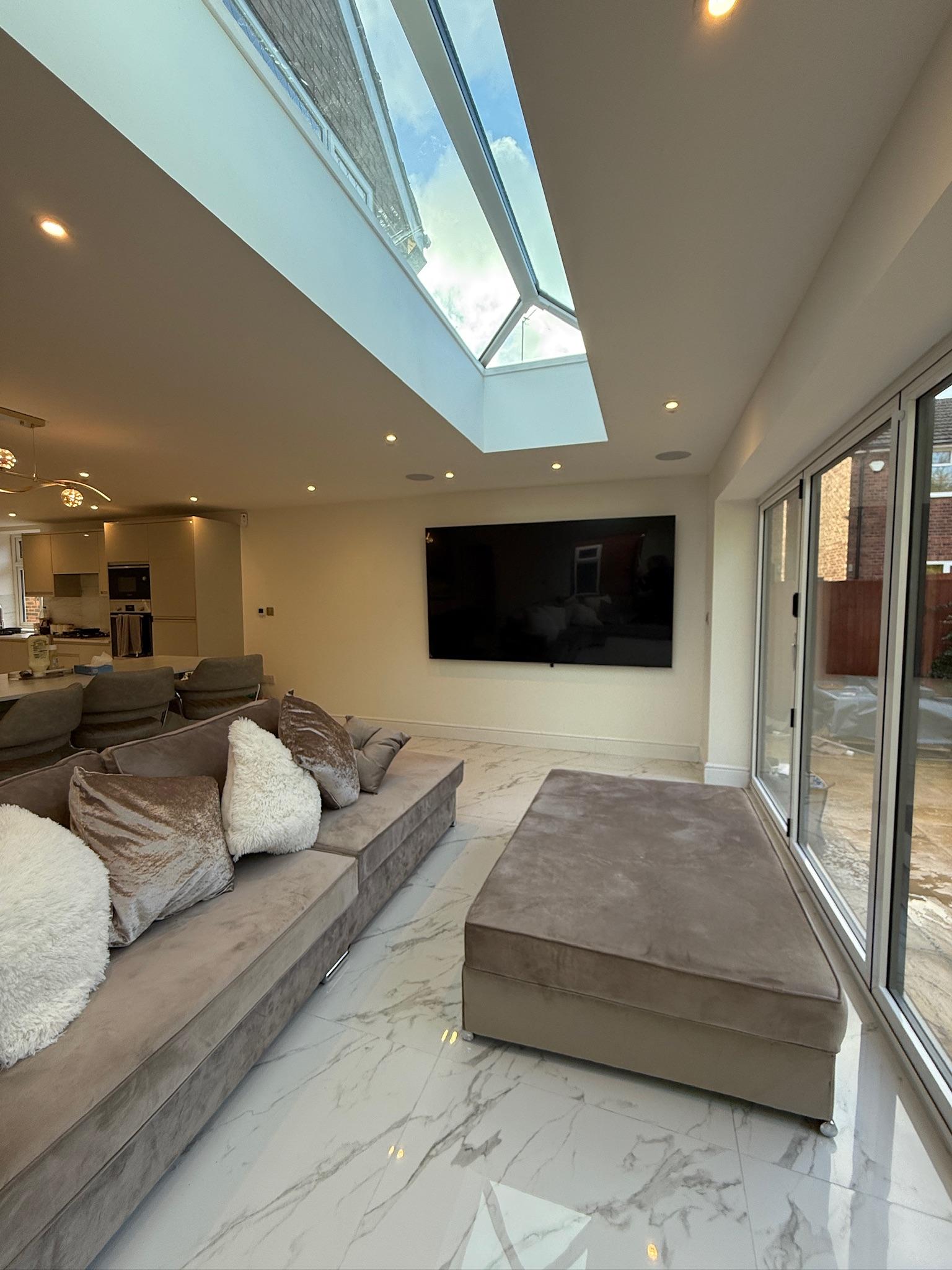 Modern rear home extension in Whitefield with large roof lantern, bifold doors, porcelain flooring and open plan family living area