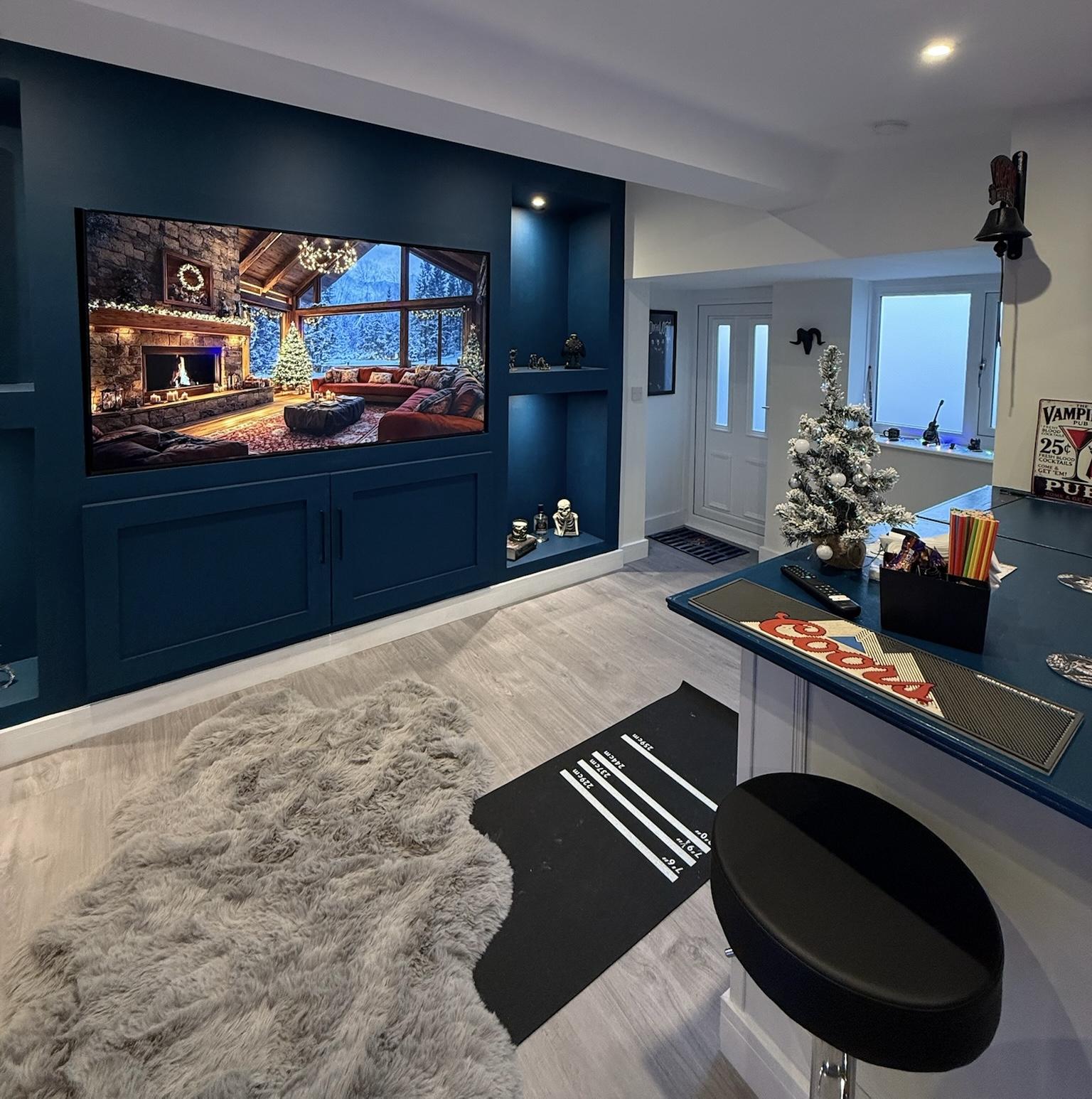 Detached garage conversion in Liverpool transformed into a modern entertainment room with bespoke media wall, fitted storage, feature lighting and bar area.