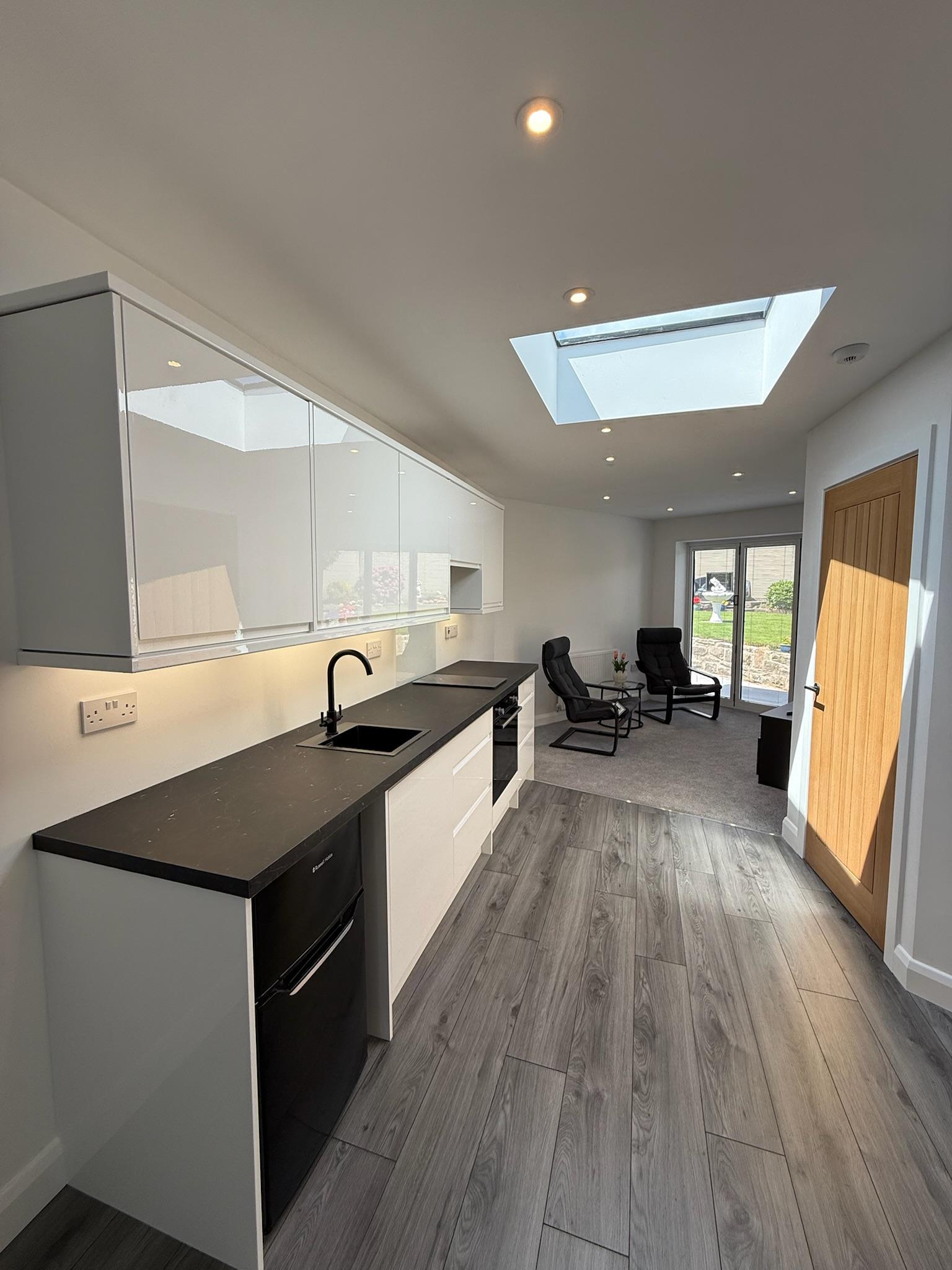 Modern open plan kitchen extension in Bury featuring roof skylights, creating a bright and spacious family kitchen diner with seamless rear extension design ideas.