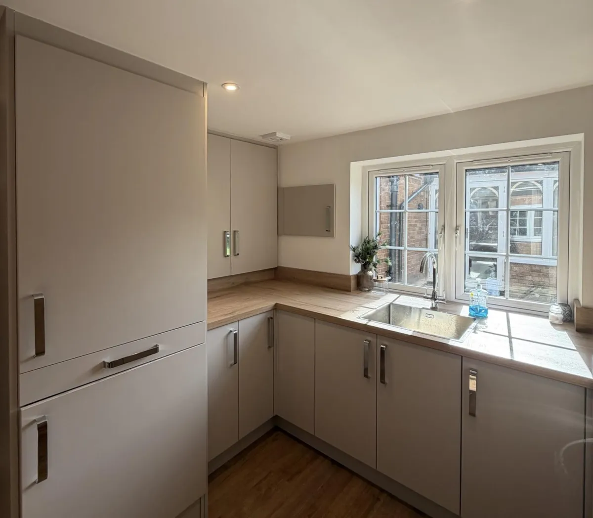 Utility room garage conversion with fitted storage cupboards, sink, worktops and natural light from large window, creating a practical laundry and storage space for a family home in Bolton