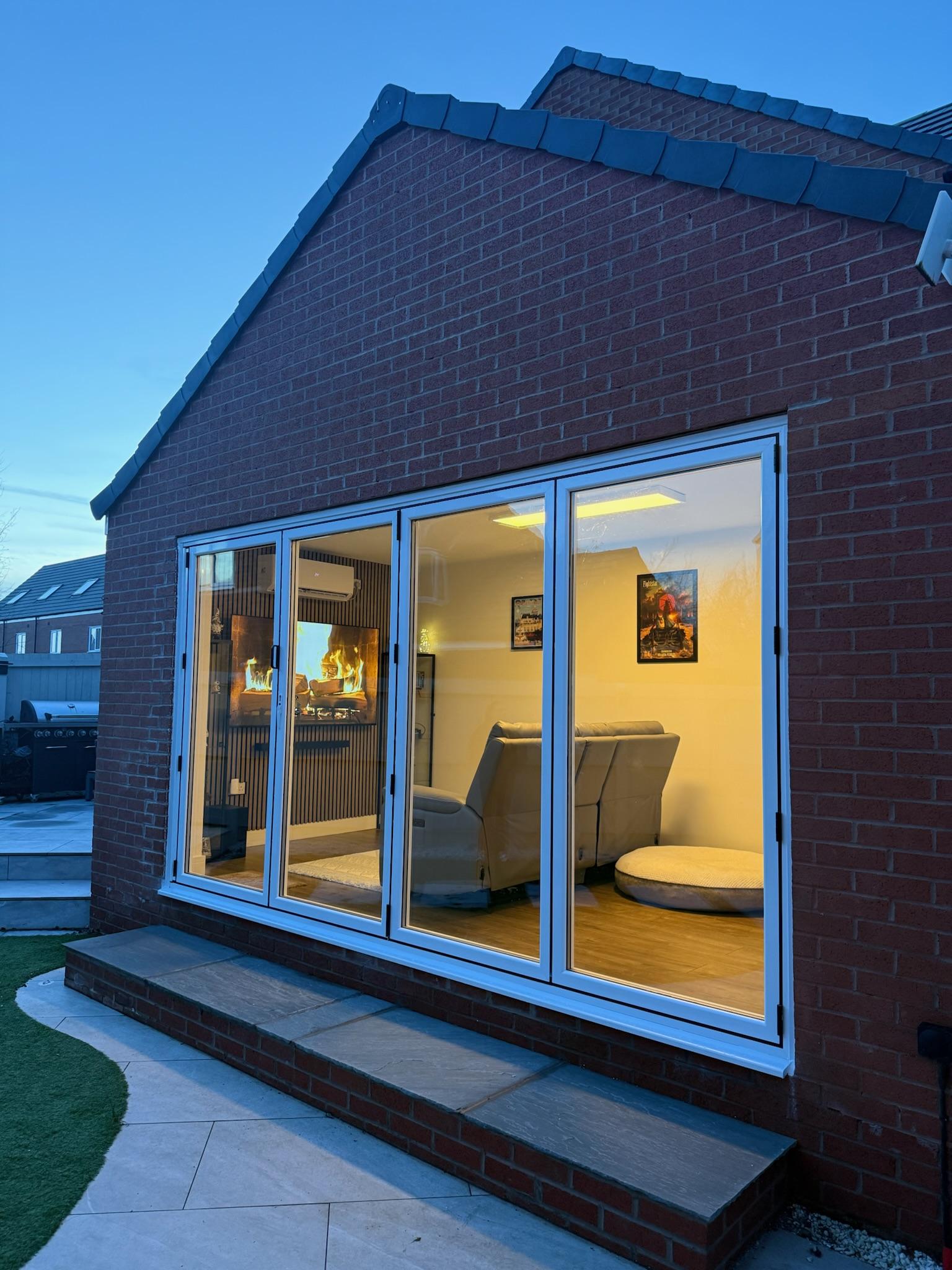 Modern living space created from a detached single garage, featuring bifold doors, a bespoke media wall and a home office area in Wigan.