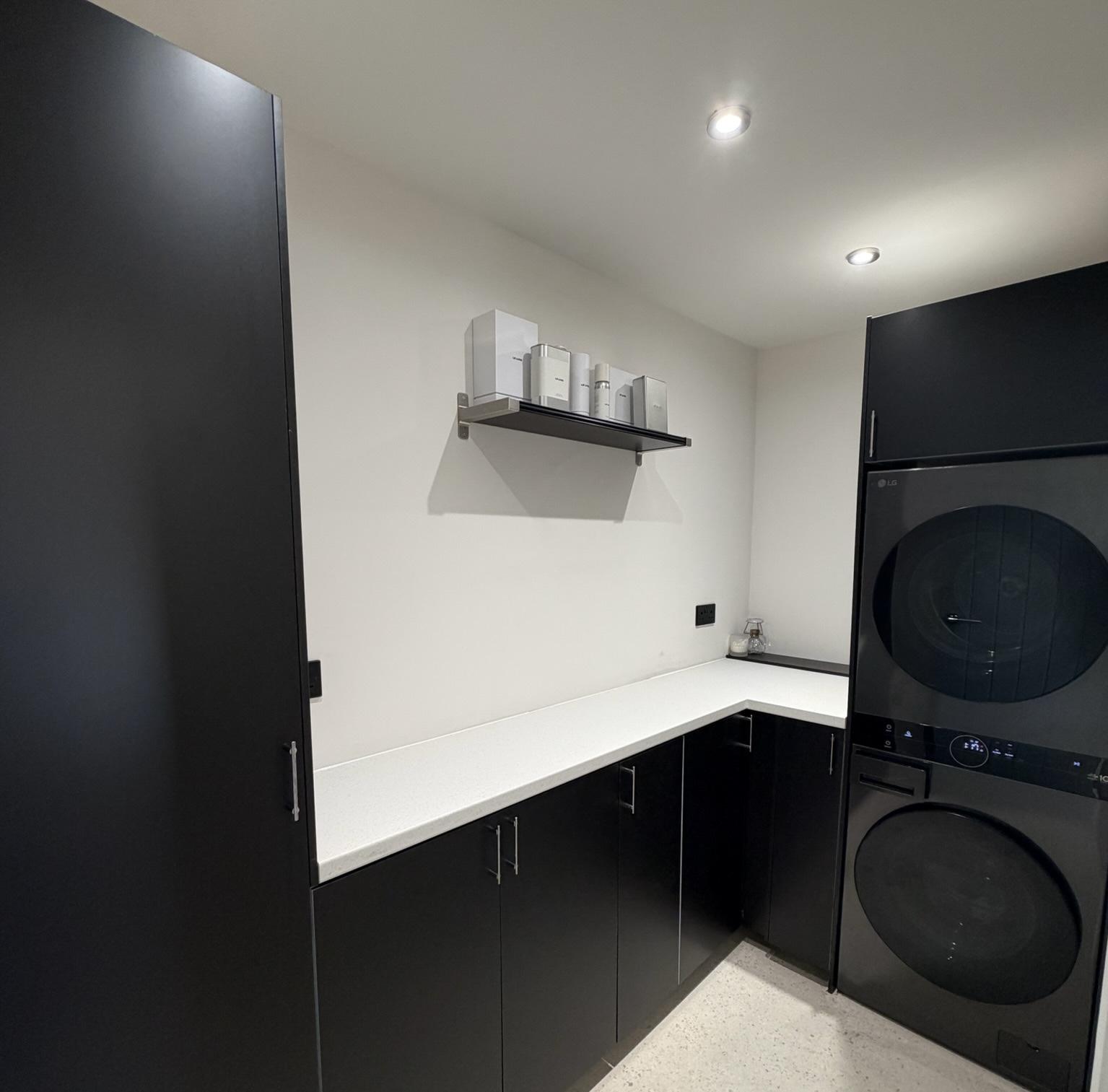 Modern utility room created within a garage conversion, with fitted storage, worktops and laundry appliances in a fully insulated living space.
