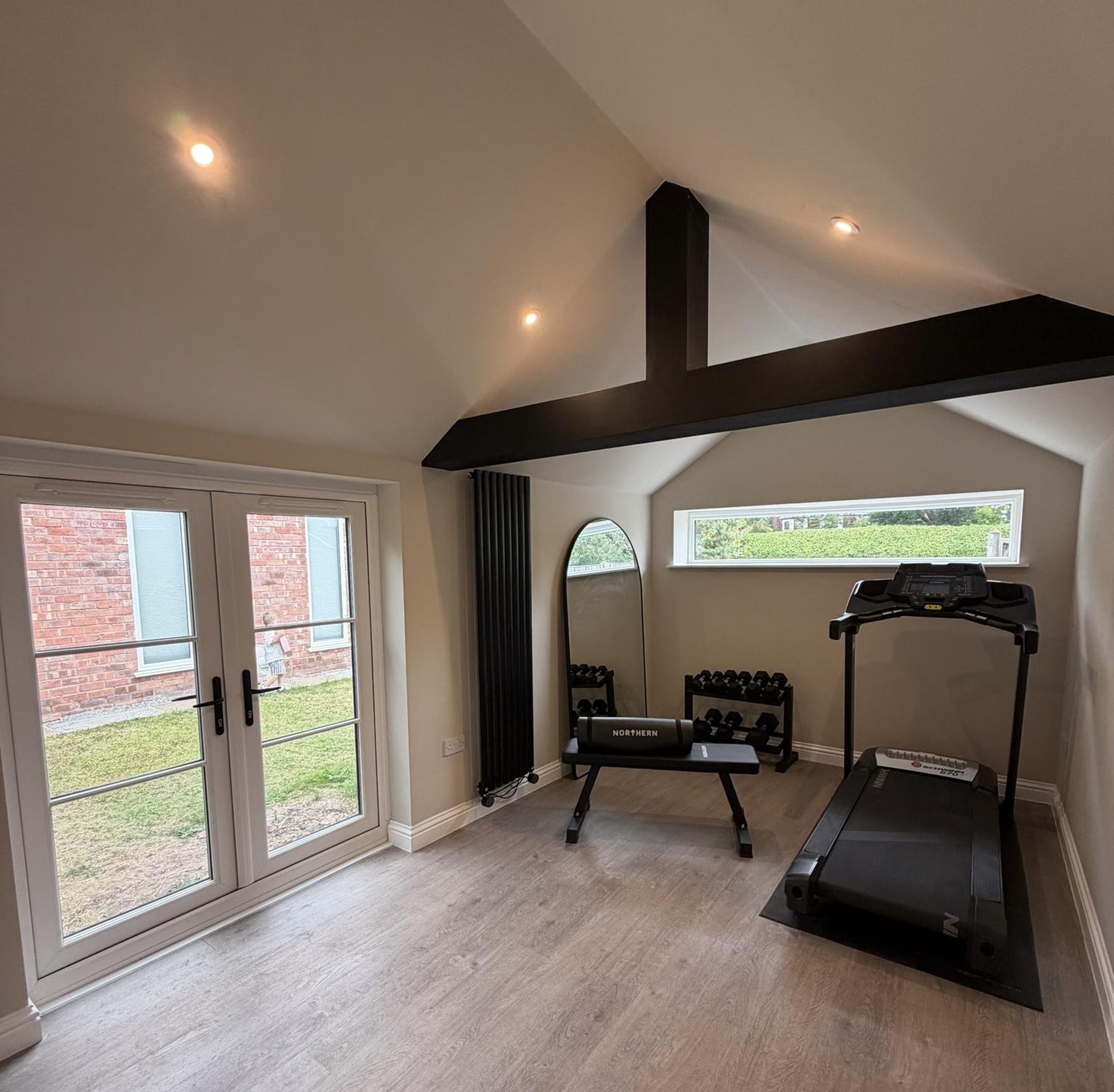 Detached single garage converted into a finished home gym in Stockport with French doors and vaulted ceiling