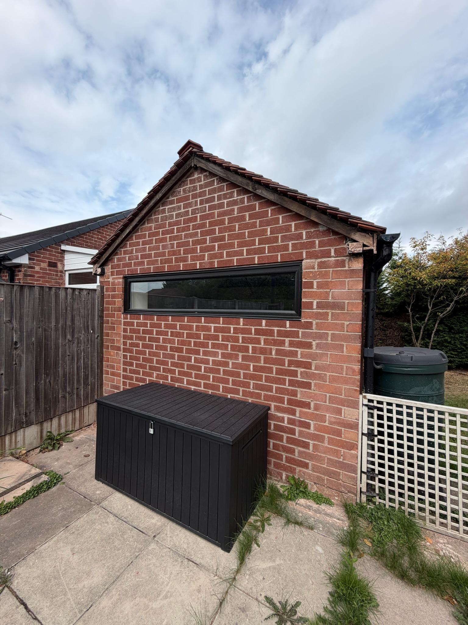Exterior of detached garage conversion in Bramhall beside a neighbouring property and boundary