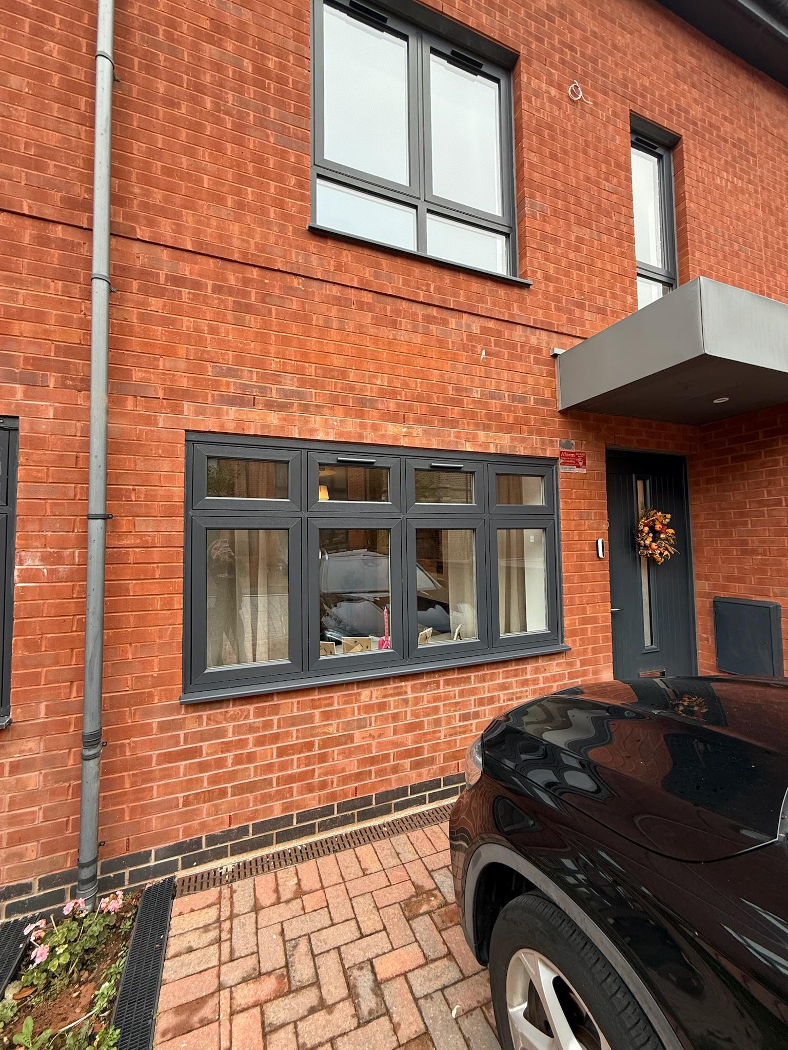 Exterior of a completed garage conversion with the former garage opening replaced by matching brickwork and a large window.