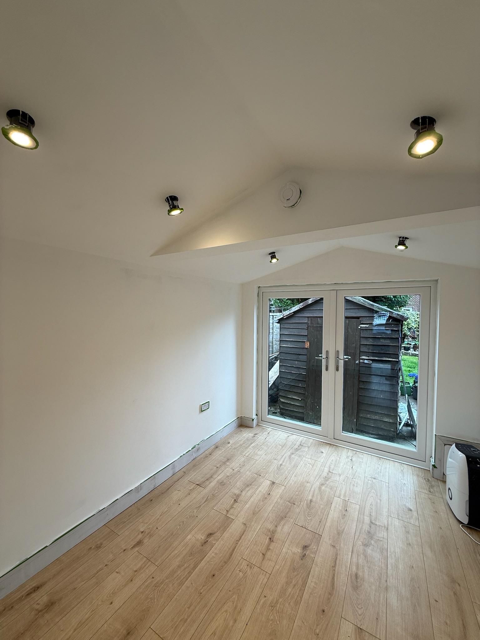 Long narrow garage conversion in Burnley transformed into an additional room with retained storage at the front and French doors to the garden.