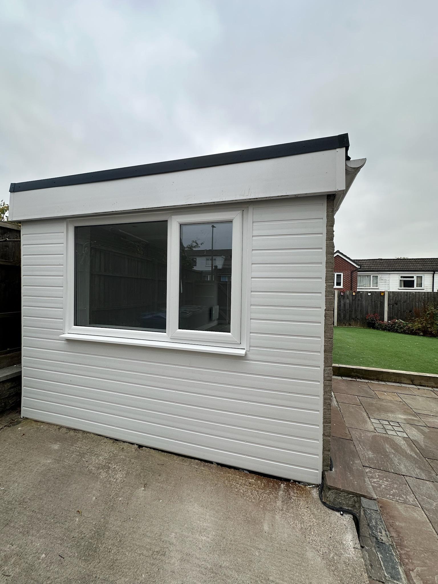 Converted prefab concrete garage with new window and external cladding in Stockport