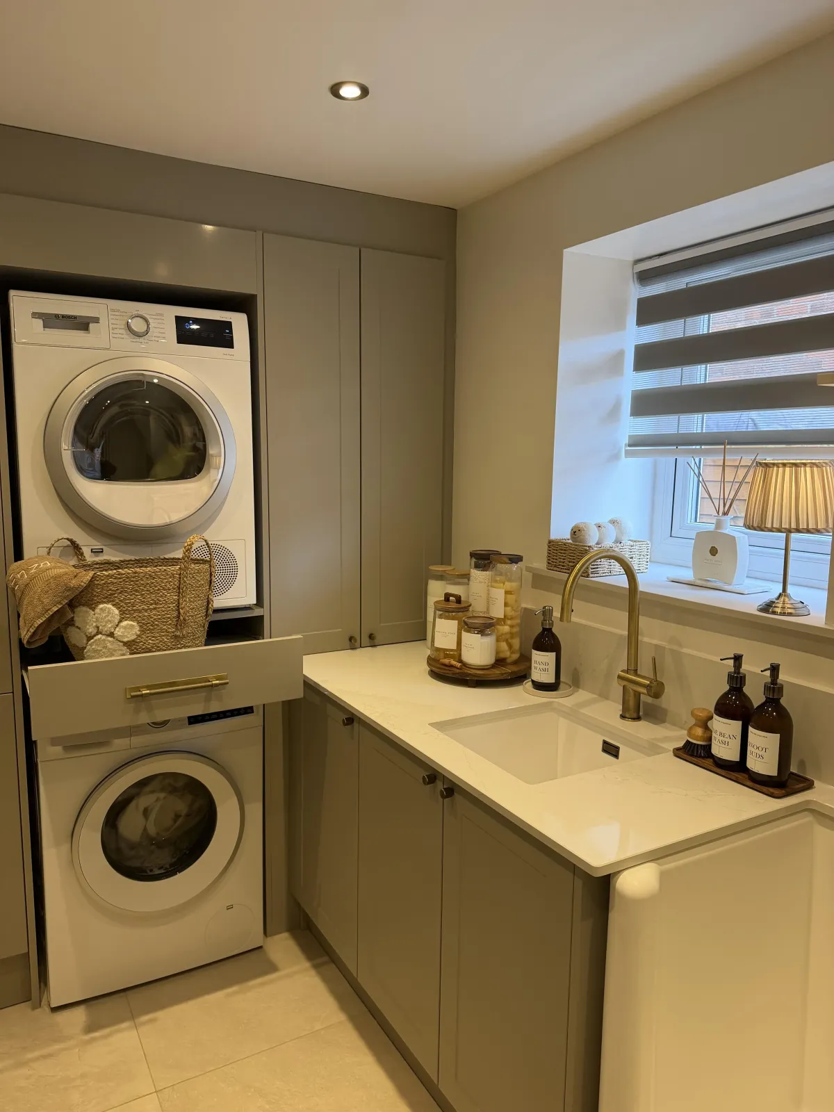 Part double garage conversion in Chorley transformed into a utility and dog wash room with fitted storage, sink and integrated laundry appliances.
