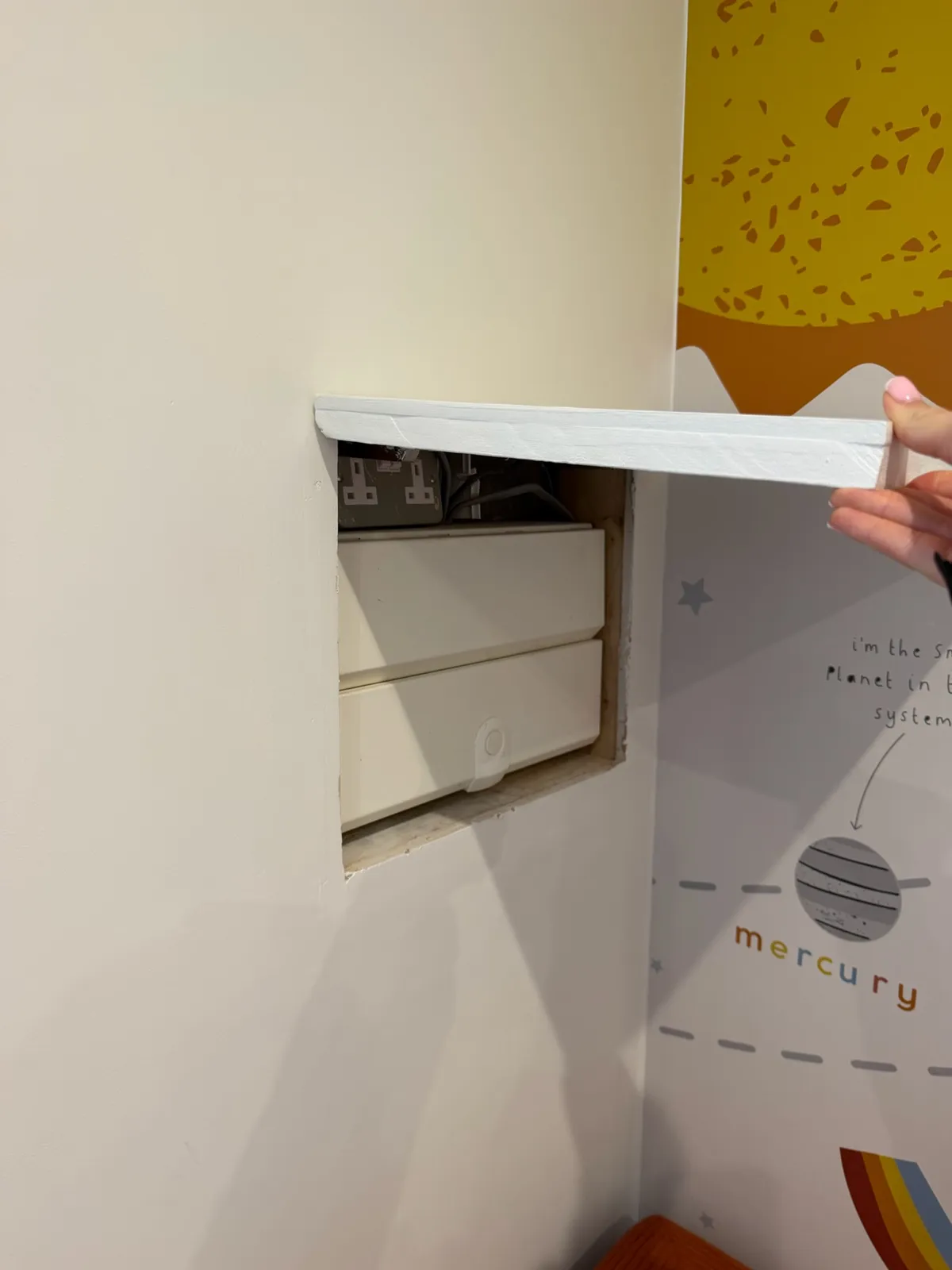 Single garage conversion in Wigan transformed into a playroom, featuring a removable wall access panel revealing existing electrical equipment.