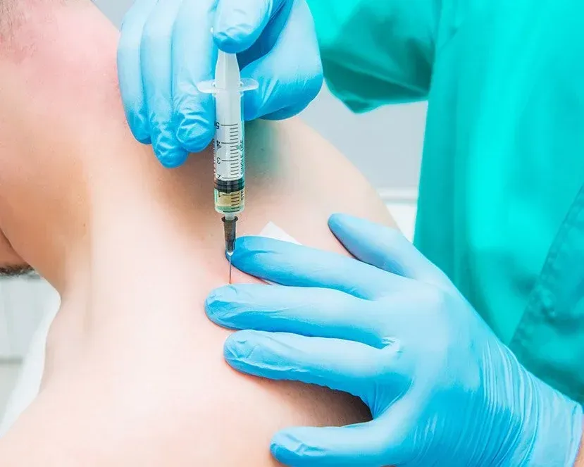 Clinician administering an ultrasound-guided regenerative injection to a patient's shoulder