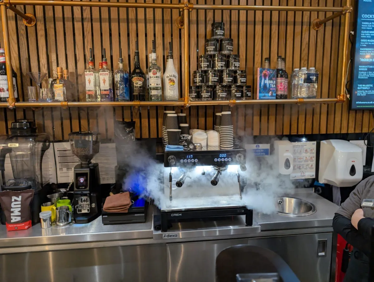 gray stainless steel mokapot on burner between two white mugs on green grass