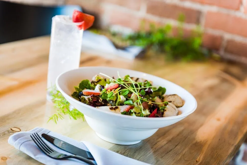 White bowl with salad on wooden table