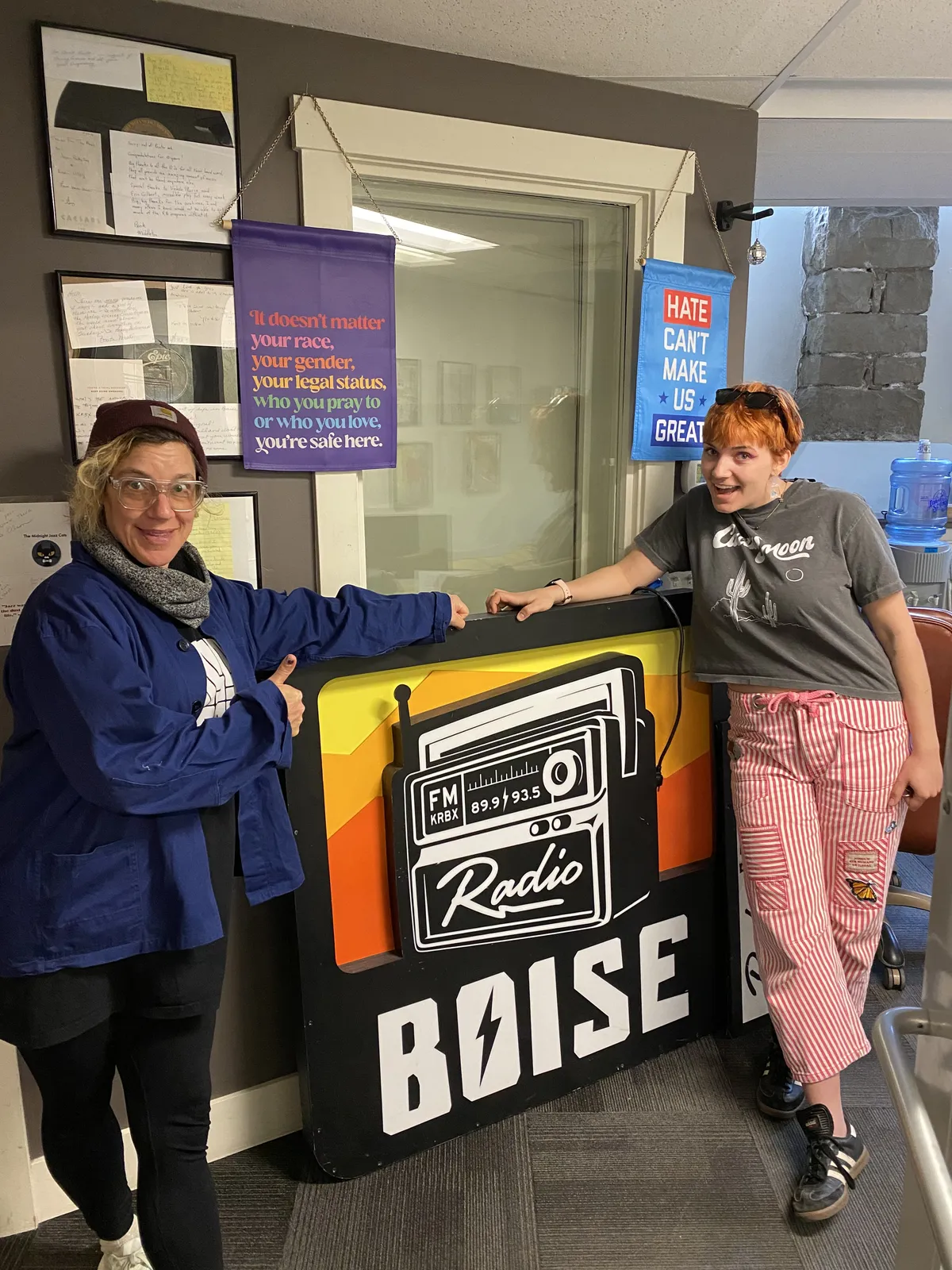 two radio boise staff standing and smiling by radio boise logo