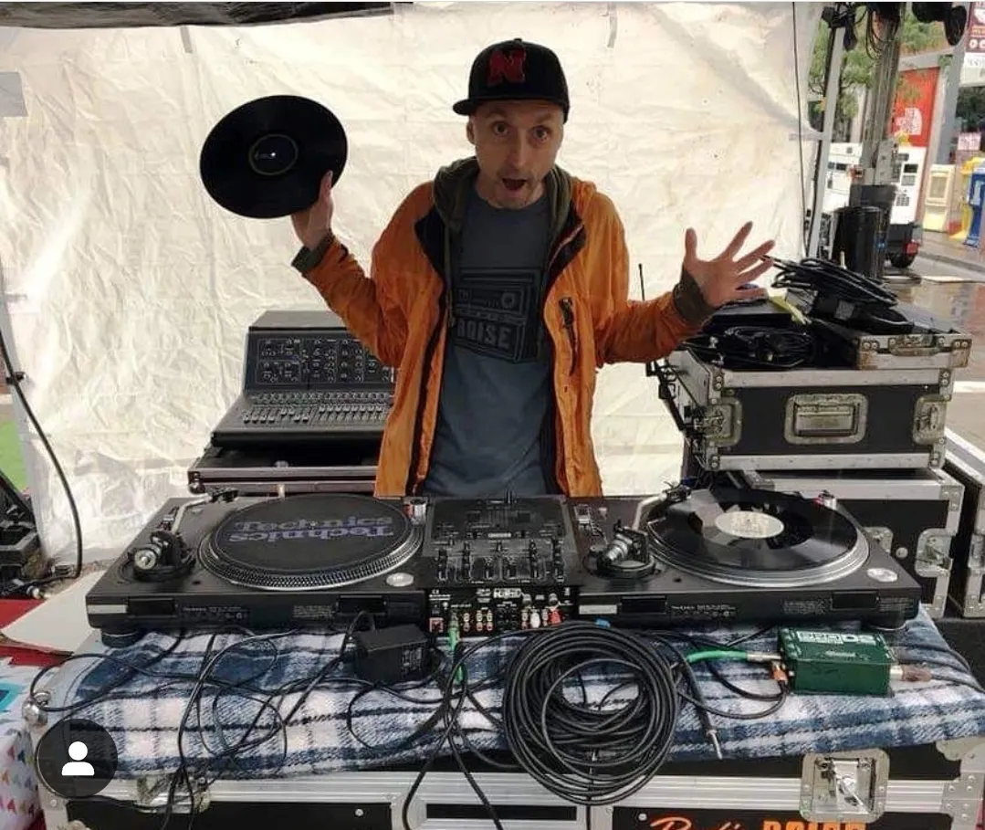 DJ holding a vinyl behind a DJ booth