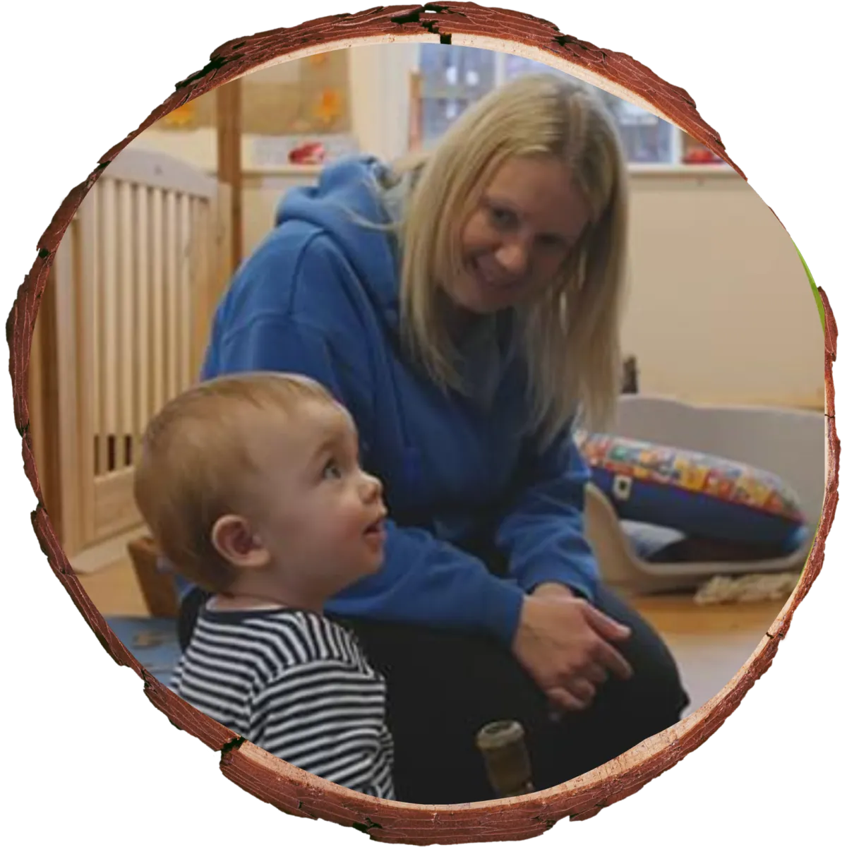 teacher sitting with baby boy who is wearing a stripy jumper.