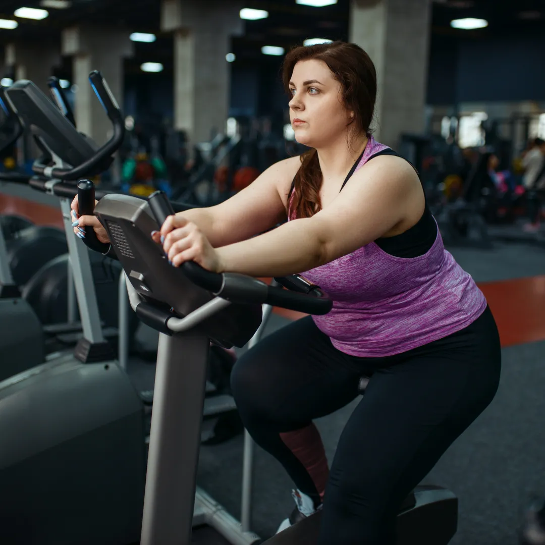 Image of overweight woman on exercise bike in a gym
