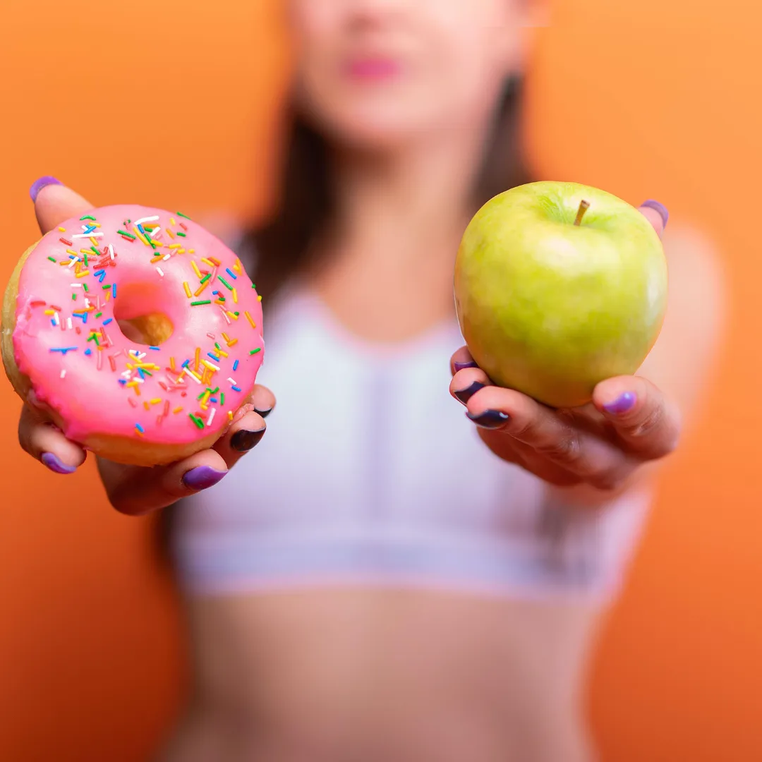 Image of woman holding donut and green apple