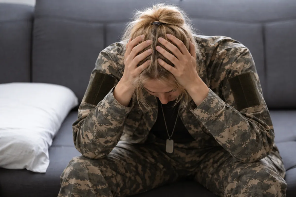 A veteran ,affected by PTSD,sitting in military uniform, bent down with his face in his hand