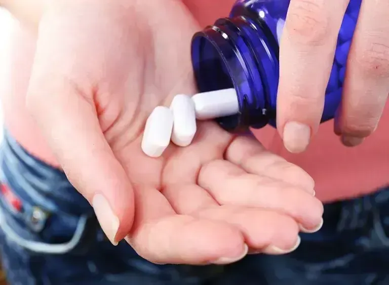 Suboxone tablets being poured from a blue prescription bottle into a patient's hand — FDA-approved buprenorphine medication for opioid use disorder treatment at Medivira in Frisco, TX