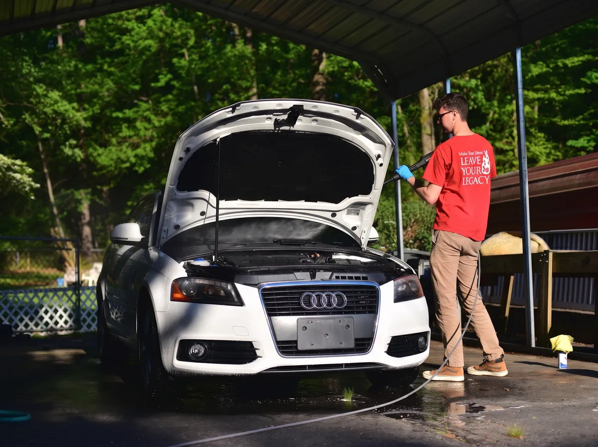 EWade Detailing technician washing a white Audi with the hood open at a customer's home