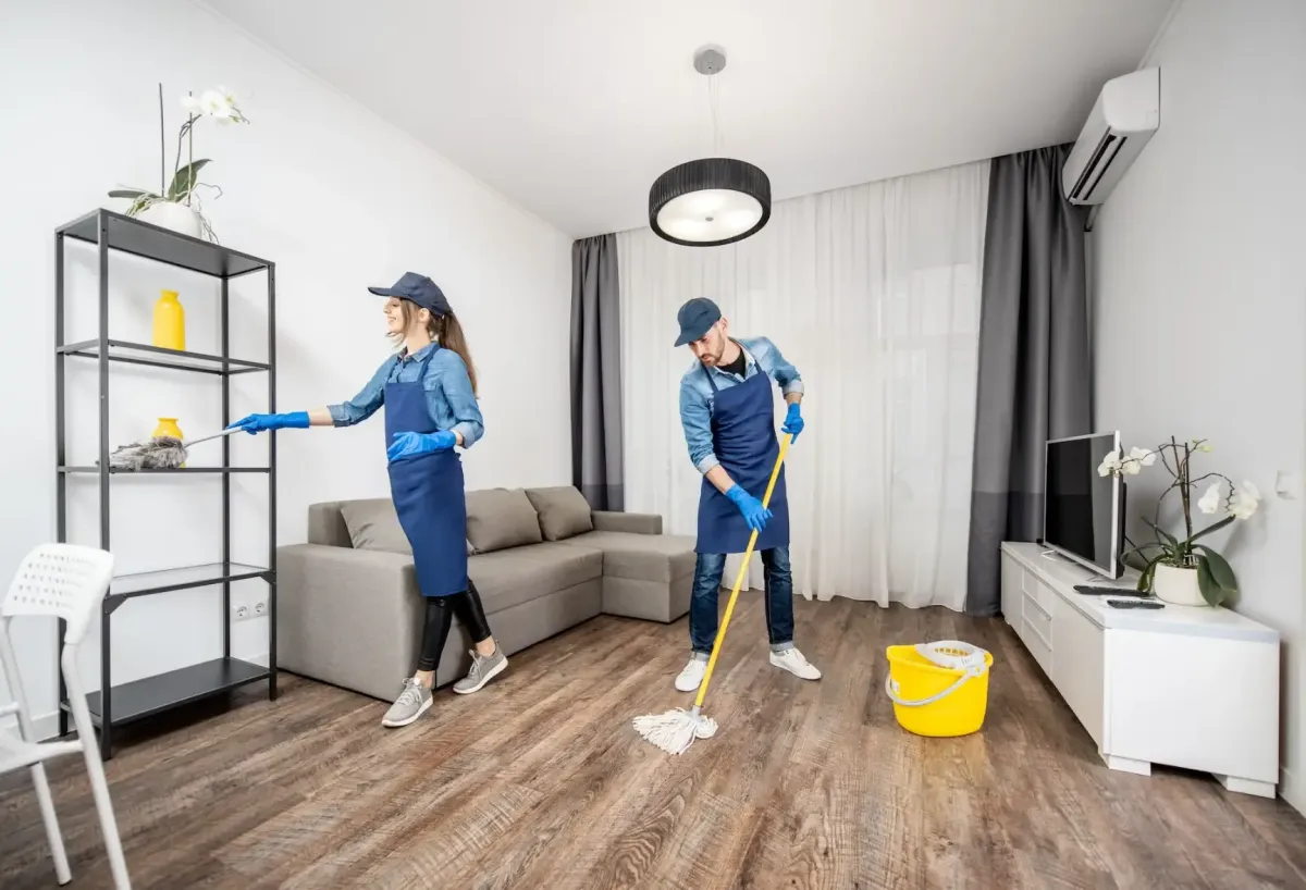 TuClean Commercial cleaning service team in professional cleaning uniforms doing floor cleaning with a mop and dusting furniture