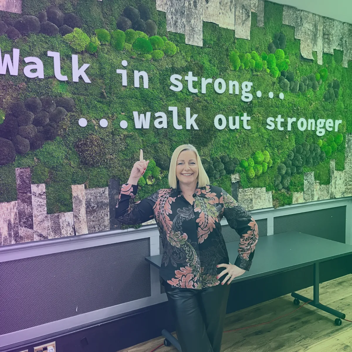 Justine in a conference room next to a motivational quote wall