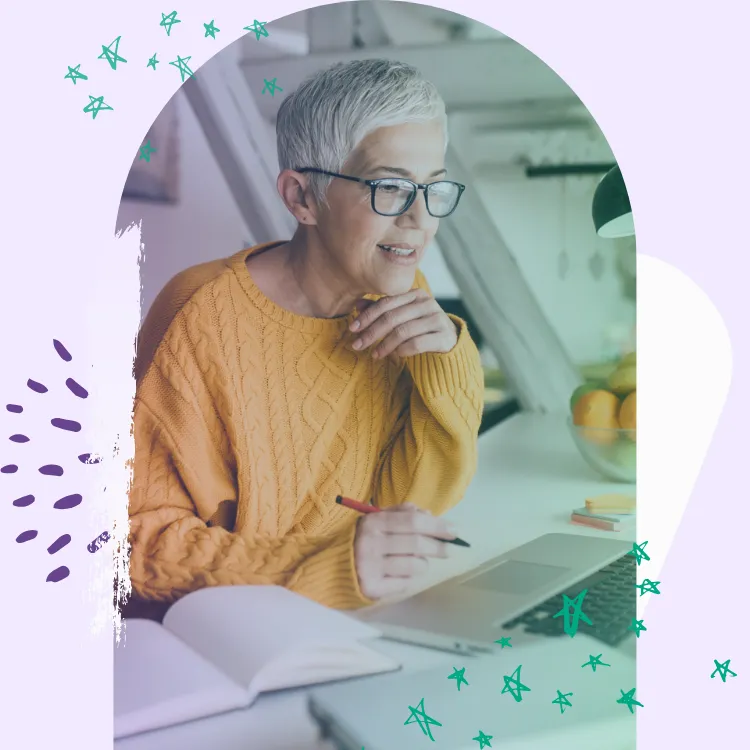 Lady over 50 n a yellow jumper working on a laptop at a desk 