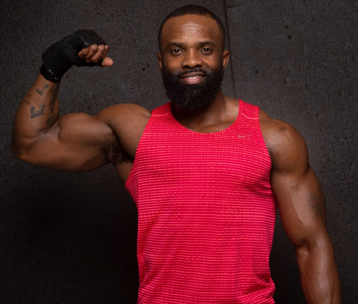 Portrait of Tabius, an athletic coach wearing Cascade Fitness gear, smiling confidently against a neutral studio backdrop.