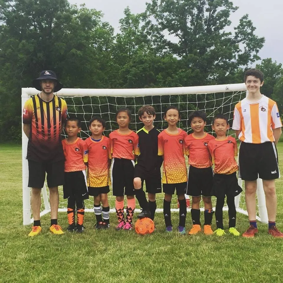 Kids playing soccer with a coach during practice