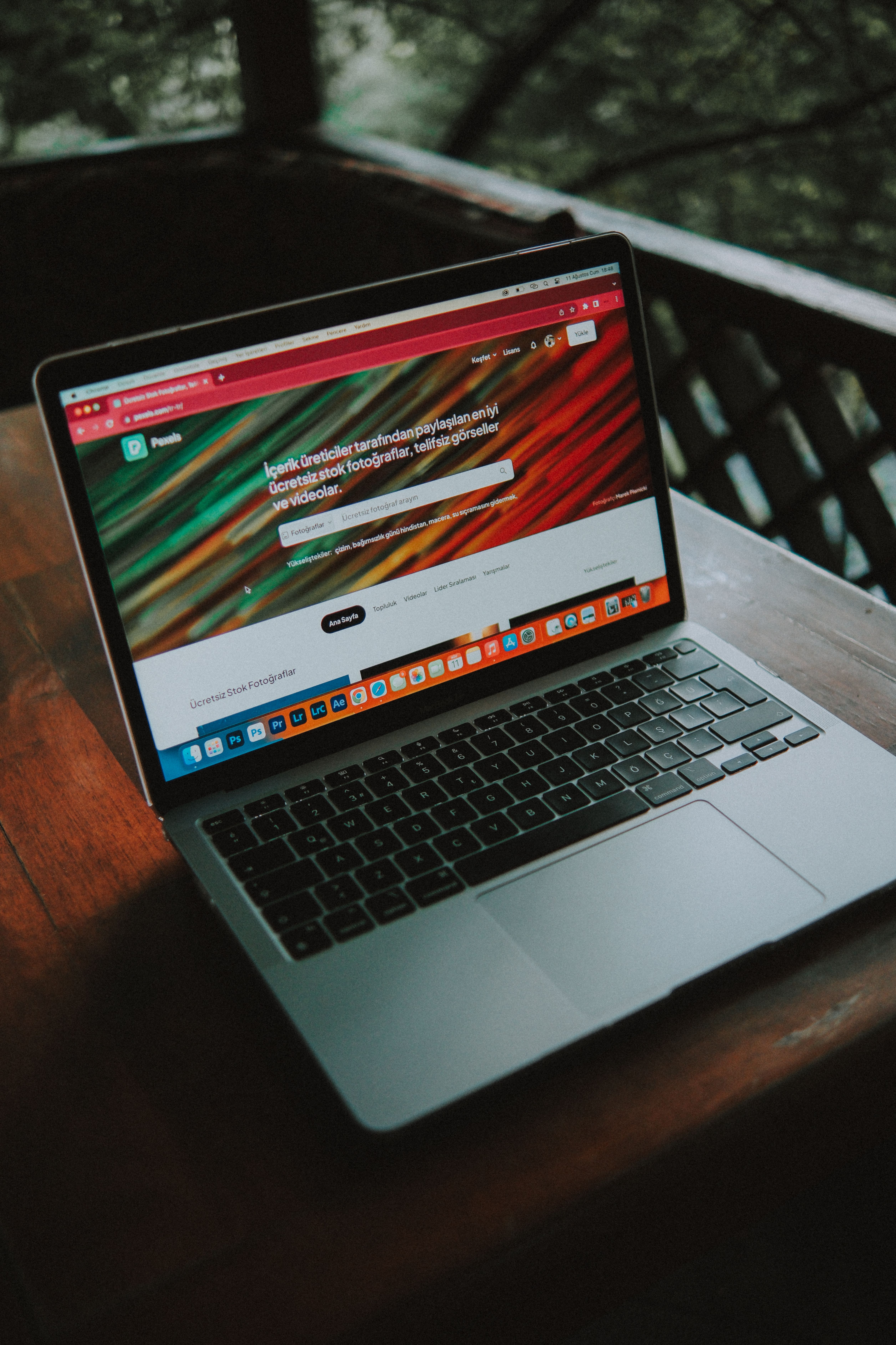 Flatlay photography showing a sleek black coffee mug, a closed silver laptop, a black pen, and a white notepad bearing 'The Quiet Edit' logo in red typography, cast with strong angled shadows.