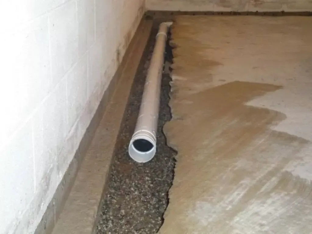 Interior French drain and sump pump installation for basement waterproofing in Kansas City home