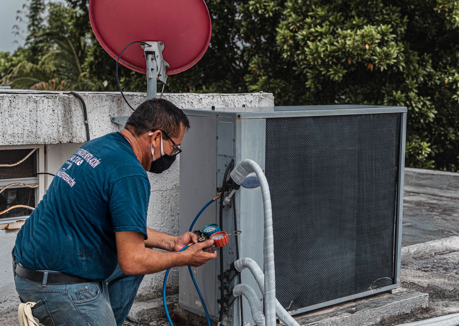 HVAC technician connecting refrigerant manifold gauges to an outdoor AC condenser unit to diagnose a low-refrigerant issue