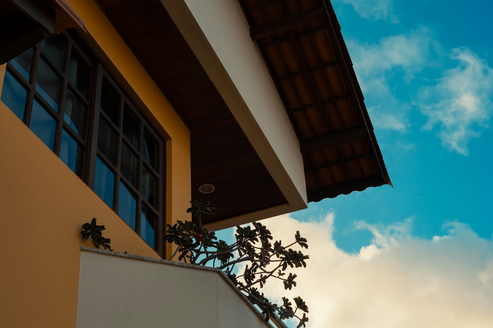 Sunlit yellow stucco Florida home exterior with tile roofline against a clear blue sky