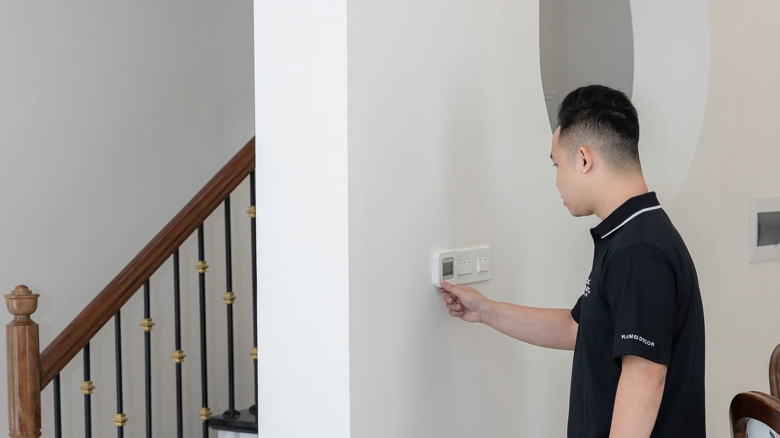 Homeowner adjusting a wall thermostat in a bright Southwest Florida home