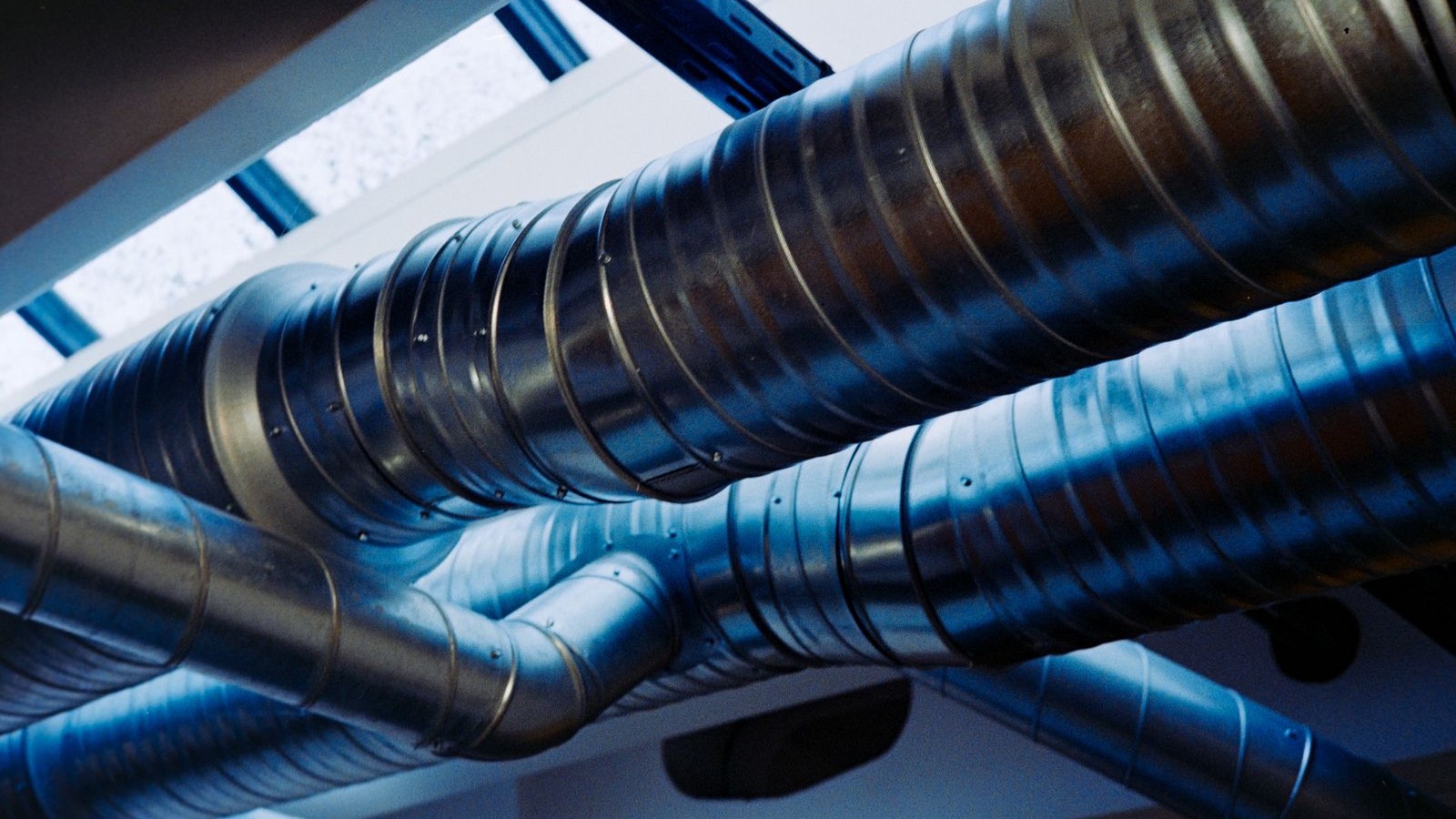 Metal supply ductwork running overhead through an unfinished ceiling space