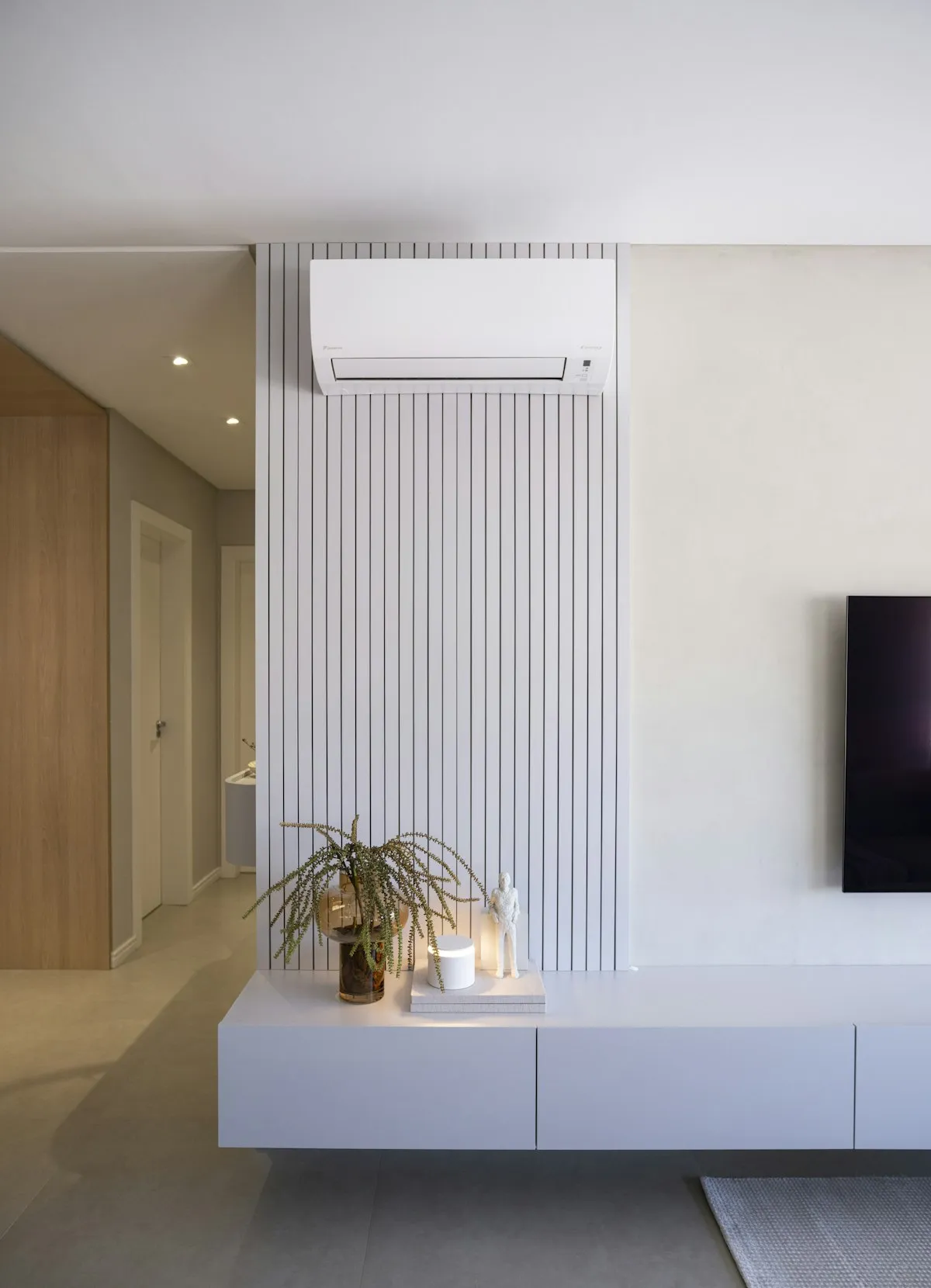 White Daikin ductless mini-split indoor unit mounted on a slatted wall above a TV console in a modern Cape Coral living room