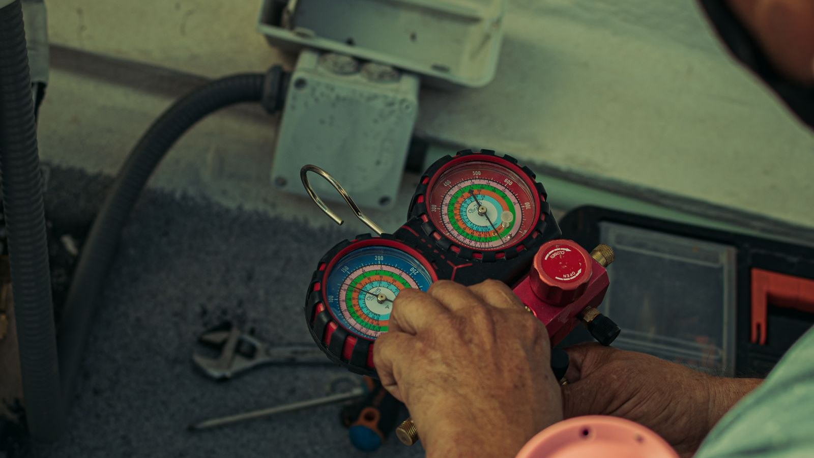 HVAC technician checking refrigerant pressures with manifold gauges on an AC system