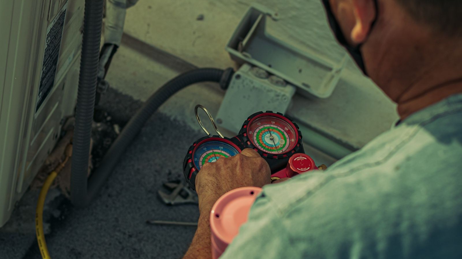HVAC technician checking refrigerant gauges on an outdoor air conditioning unit