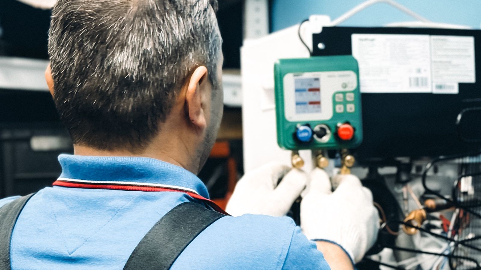 HVAC technician using digital manifold gauges to service an indoor air handler