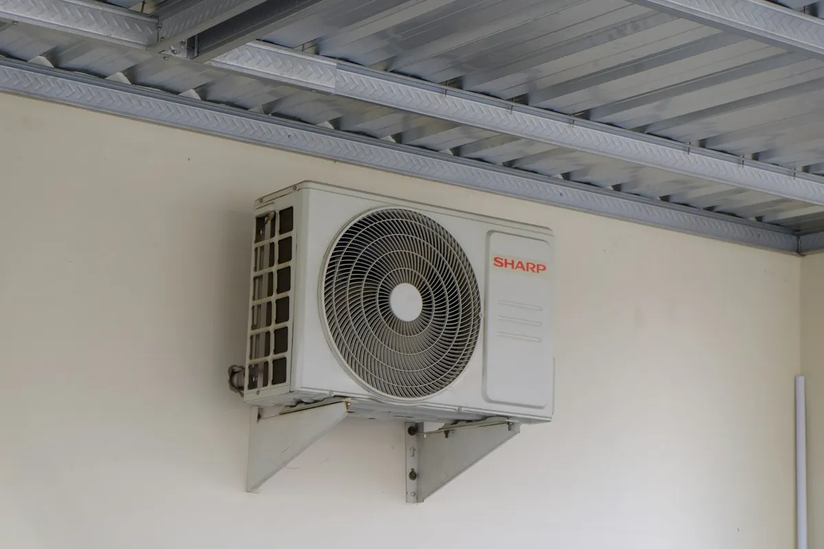 Residential mini-split AC condenser mounted under a carport ceiling